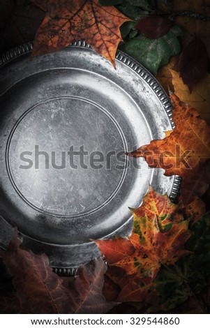 Old metal plate surrounded autumn leaves and pumpkins with film filter effect