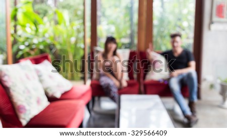 image blur background, people sitting in living room, interior decoration cafe with red sofa furniture and green garden background