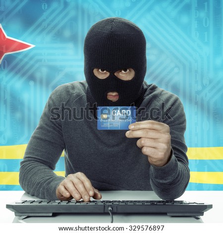 Dark-skinned hacker with credit card in hand and flag on background - Aruba