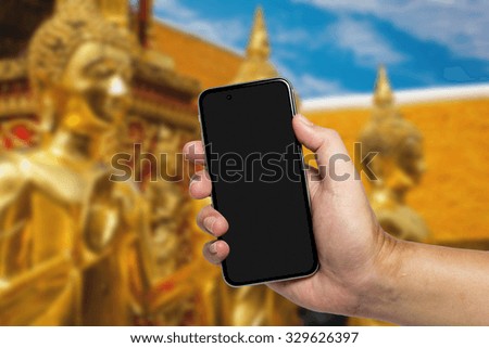 Closeup image with male hand hold and touch screen smart phone, tablet,cellphone over blurred Religious background.