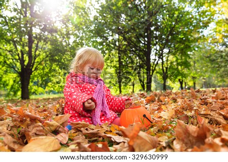 cute little girl playing with autumn fall leaves