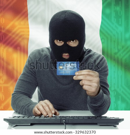 Dark-skinned hacker with credit card in hand and flag on background - Ivory Coast