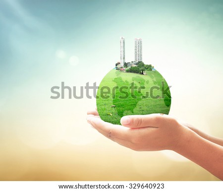 World environment day concept: The city on green earth globe of grass in human hands over blurred beautiful nature background