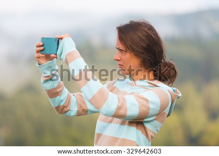 Young woman using smartphone to photograph the surroundings.