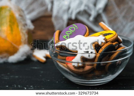 Dark picture of bowl of Halloween cookies at spiderweb and ghost background. Ghost at front