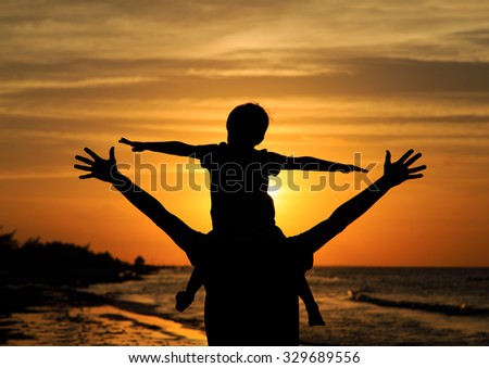 father and son having fun on sunset beach
