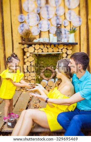 parents with little daughter sitting on a background of wooden fireplace