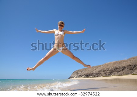 Happy girl jumping on the beach, Fuerteventura, Canary Islands Spain