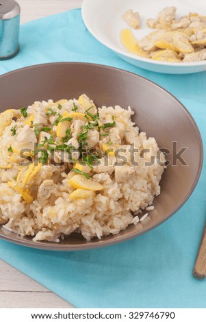 a brown bowl with rice cooked in chicken stock and stir fried with chicken breast, zuchnini, garlic and spices garnished with parsley