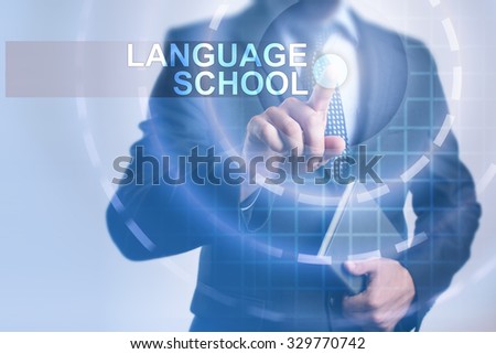 Businessman pressing button on touch screen interface and select Language school. Business, internet, technology concept.