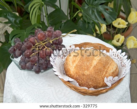 This a still life photo of grapes and bread.