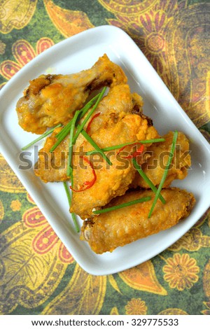 Fried chicken wings with spices served on white dish and flowery background