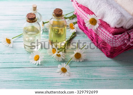 Spa setting. Aroma oil with chamomile and towels on  turquoise painted wooden background. Selective focus.