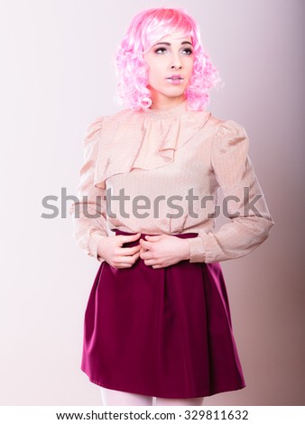 Portrait woman with pink wig creative visage makeup posing on gray background