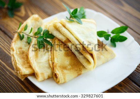 many thin pancakes on a plate on a wooden table