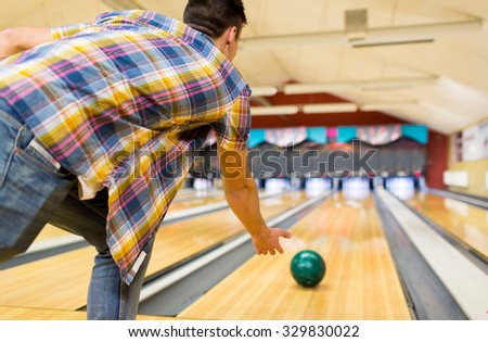 people, leisure, sport and entertainment concept - close up of young man throwing ball to alley in bowling club