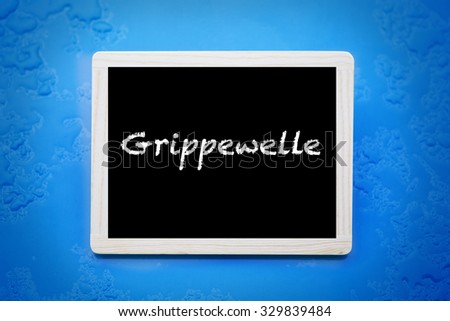 blackboard with german word 'Grippewelle' (flu season) on blue wet background