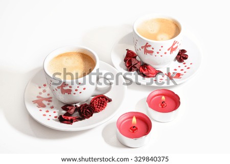 Two Christmas  cups of espresso coffee with red candles on white background