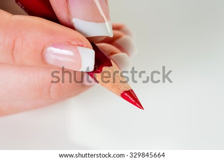 a hand holding a red pen. symbolic photo for savings and budegt cuts.