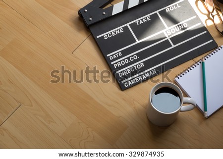 clapper board with blank paper and cup of coffee on wooden background.