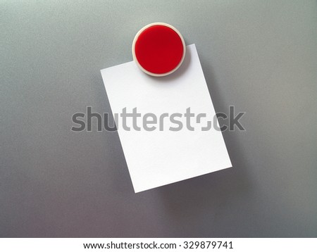 circle red plastic fridge magnet with blank white note paper on gray metal refrigerator door background, notepaper for writing messages to communicate and reminder, close up with copy space for text Royalty-Free Stock Photo #329879741