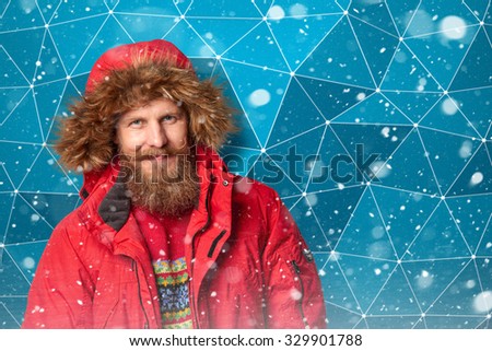 Bearded man wearing red winter jacket with hood in winter snow over ice abstract background