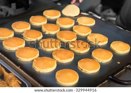 Fresh pancakes, cooking on a street food vendor's hot griddle at a stall.