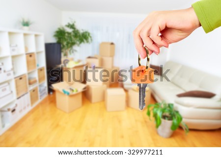 Hand with house key. Real estate and moving background. Royalty-Free Stock Photo #329977211