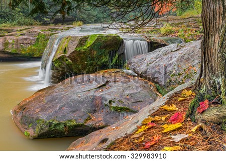Water pours over boulders with colorful autumn leaves at a waterfall just upstream from O Kun De Kun Falls, named after an Ojibway chief, in Michigan's scenic western Upper Peninsula.