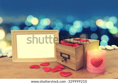picture frame and red hearts are pouring from wooden box  on blur bokeh light in city in blue tone background