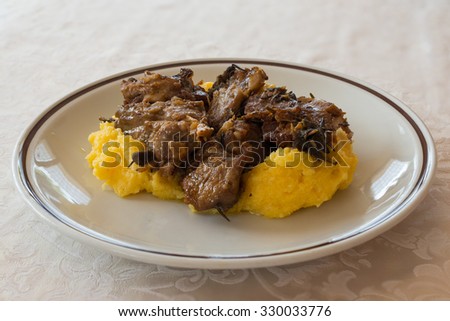 in the picture typical italian food ,roasted goat and Polenta on white dish at restaurant.