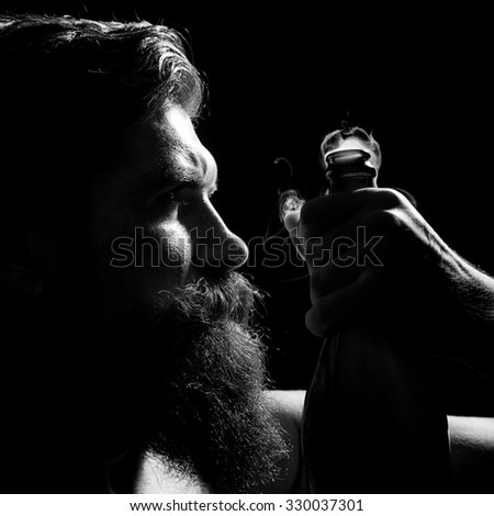 Closeup portrait side view of one senior serious man with long lush beard holding uncorked glass champagne wine bottle with smoke in studio on black background, square picture