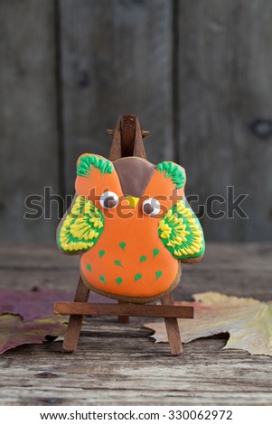 Homemade gingerbread cookie in the form of an orange owl on the wooden table. Space for text and selective focus.