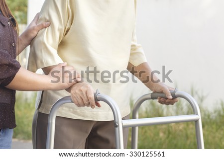 senior woman using a walker with caregiver Royalty-Free Stock Photo #330125561
