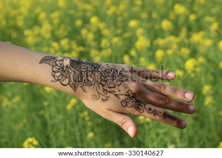 Henna on girl hand on greenish yellow background