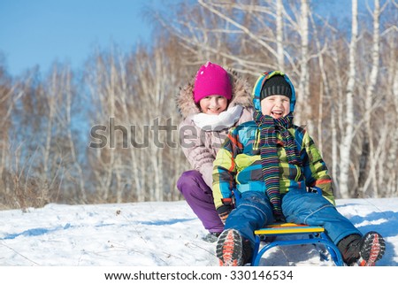 Two cute kids riding sled and having fun