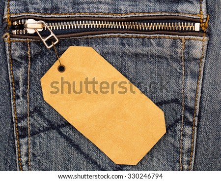 Rumpled brown paper label  with brown pin on destroyed torn blue jeans pocket background  