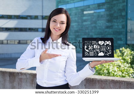 young beautiful business woman showing laptop with multimedia icons and applications on screen