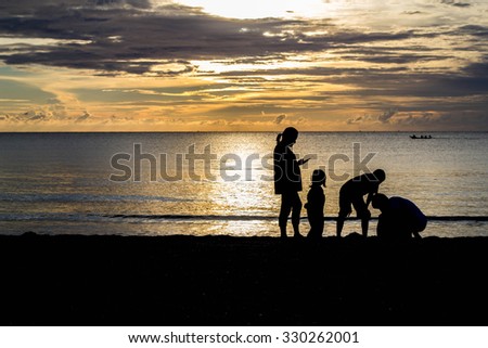 silhouette of family on the beach at dusk.