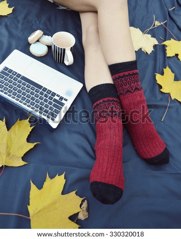 Soft photo of woman on the bed with notebook,  cup of coffee, top view point.Female legs in warm woolen socks