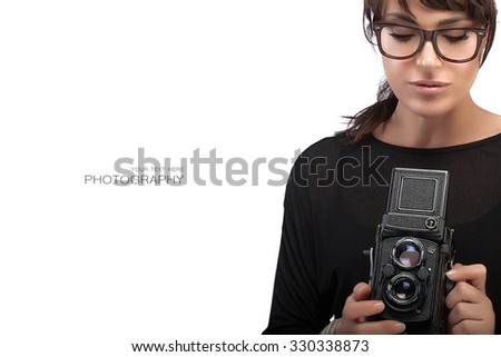 Beautiful Young Woman Wearing Black Clothes and Glasses Capturing Photo Using Vintage Camera. Isolated on White Background with Sample Text Copy Space