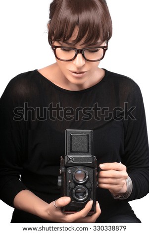 Attractive Young Woman Wearing Black Clothes and Glasses Capturing Photo Using Vintage Camera. Isolated on White Background