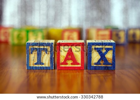 Word of TAX spelled with colorful wooden alphabet blocks.Selective focus,shallow depth of field.