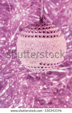 
Christmas ball close up on a blurred background of tinsel. Photo toned in purple. Selective focus
