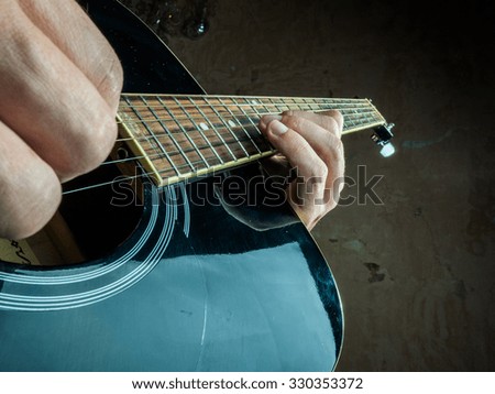 Closeup photo of an acoustic guitar played by a man. Only hands visible. Unrecognizible guitar player.