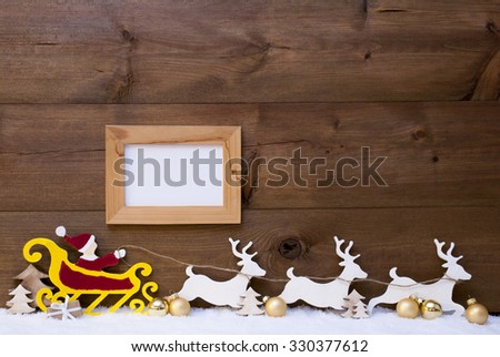 Christmas Card With Decoration Like Red Santa Claus With Yellow Sled And White Reindeer On Snow. Brown Vintage Wooden Background With Picture Frame For Copy Space And Golden Christmas Balls. 