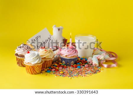 Fun kid birthday concept. Sweets, cupcakes and cup of milk with message happy birthday