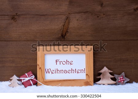 Brown Christmas Card With Picture Frame On White Snow. Red German Text Frohe Weihnachten Means Merry Christmas, Tree, Christmas Gift And Star. Rustic Wooden, Retro Vintage Background