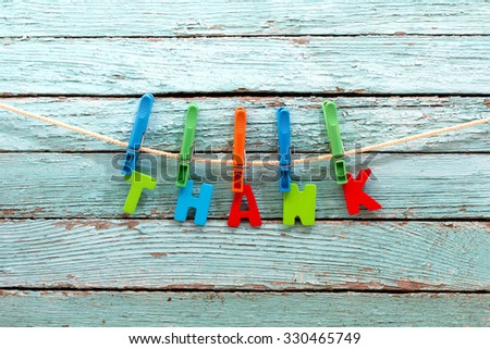 word thank fasten clothespins on a rope behind a wooden background