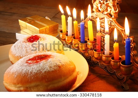 image of jewish holiday Hanukkah with menorah (traditional Candelabra), donuts and wooden dreidels (spinning top). retro filtered image
